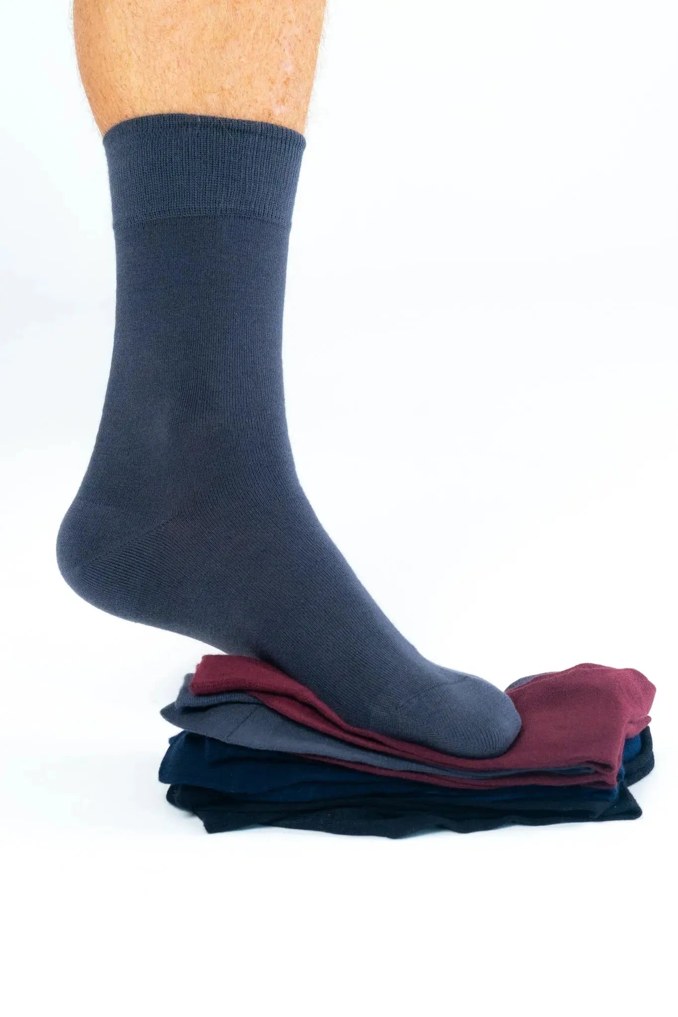 Grey bamboo business sock shown worn, placed atop multi-color sock pack including maroon, navy, and black; comfortable sustainable fashion