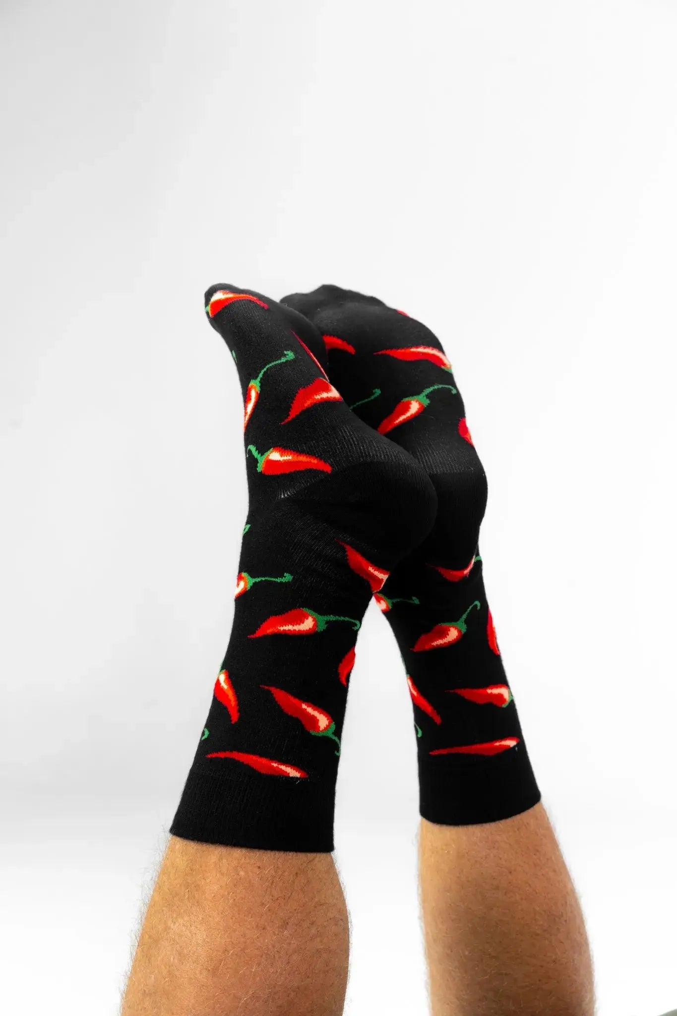 Black bamboo socks with vibrant red chilli pepper pattern worn on feet, comfortable eco-friendly socks