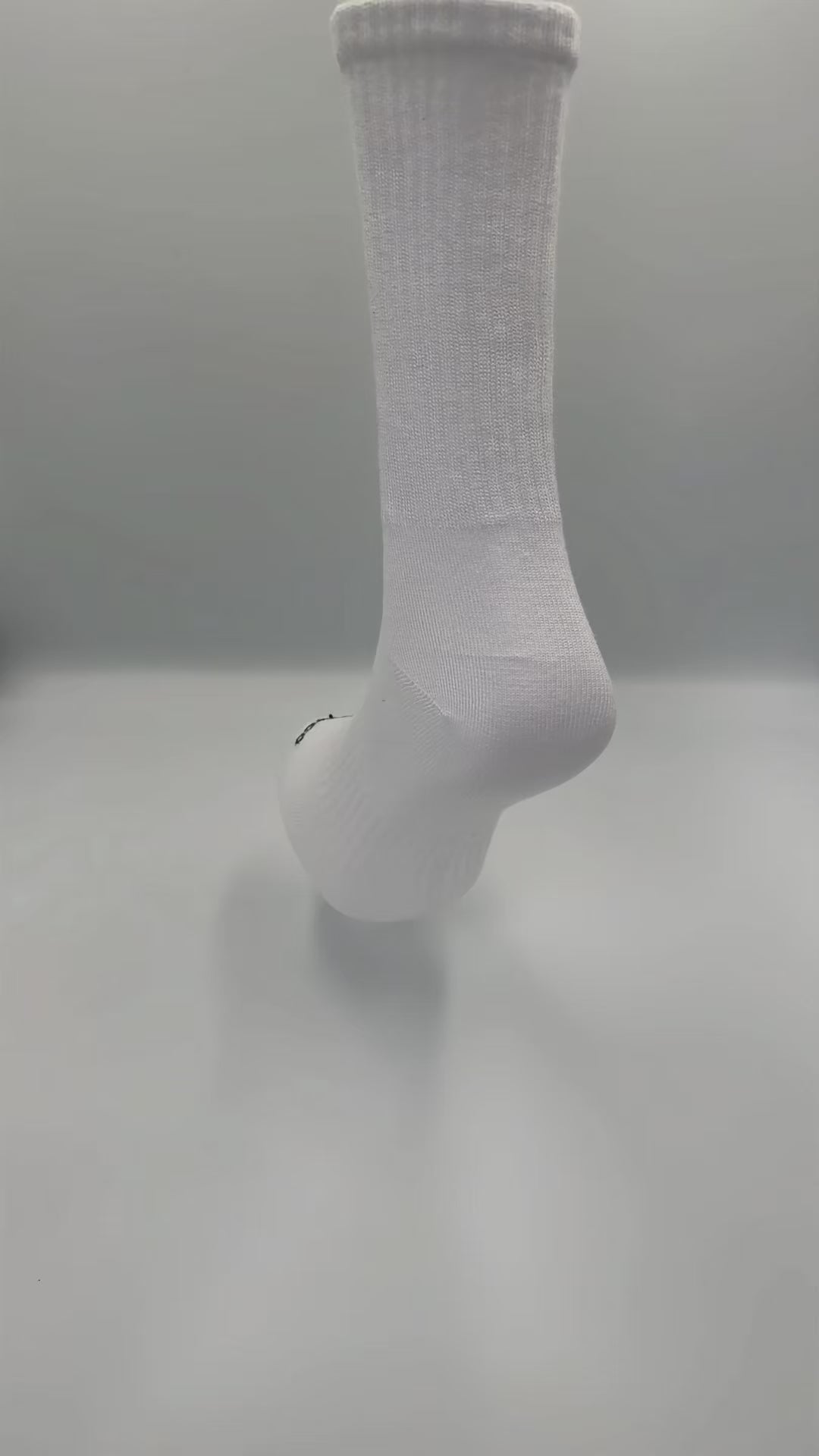 360-degree video of a white bamboo crew sock on display stand, showcasing fit and texture