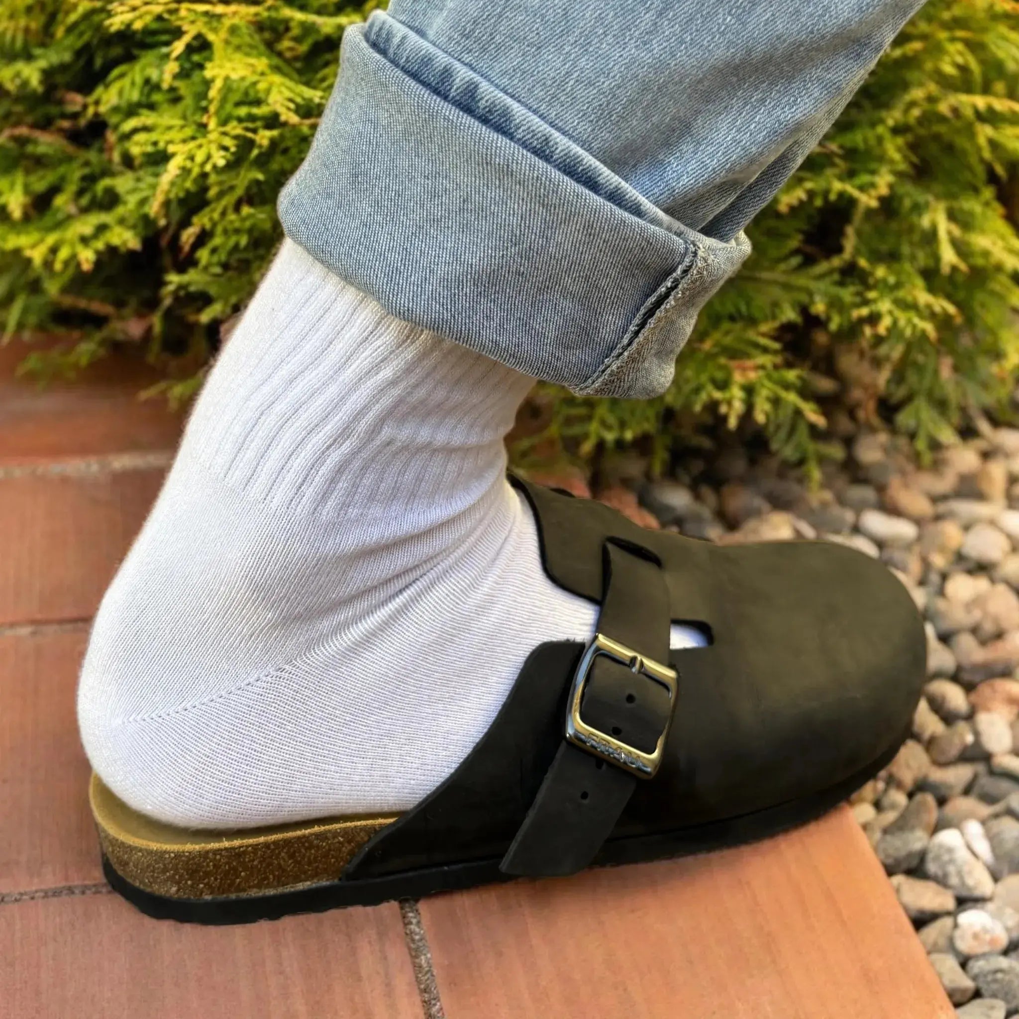 White ribbed Luxebamboo crew socks styled with black buckle clogs and rolled denim jeans outdoors