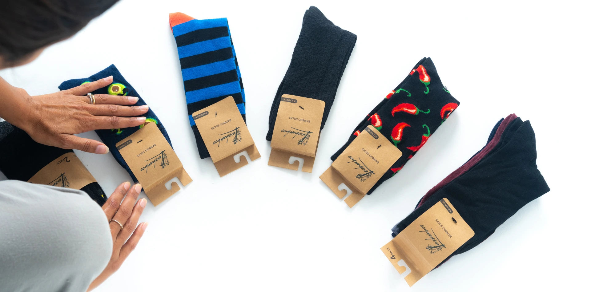 Luxebamboo bamboo socks in various designs including chilli, avocado, and striped patterns being arranged on white background.